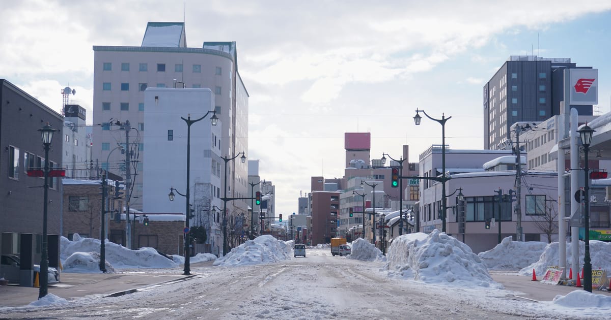 1 月的青森市街,柏油路面覆蓋壓實的雪、人行道旁堆著除雪後的雪牆,是日本雪國冬季的日常街景