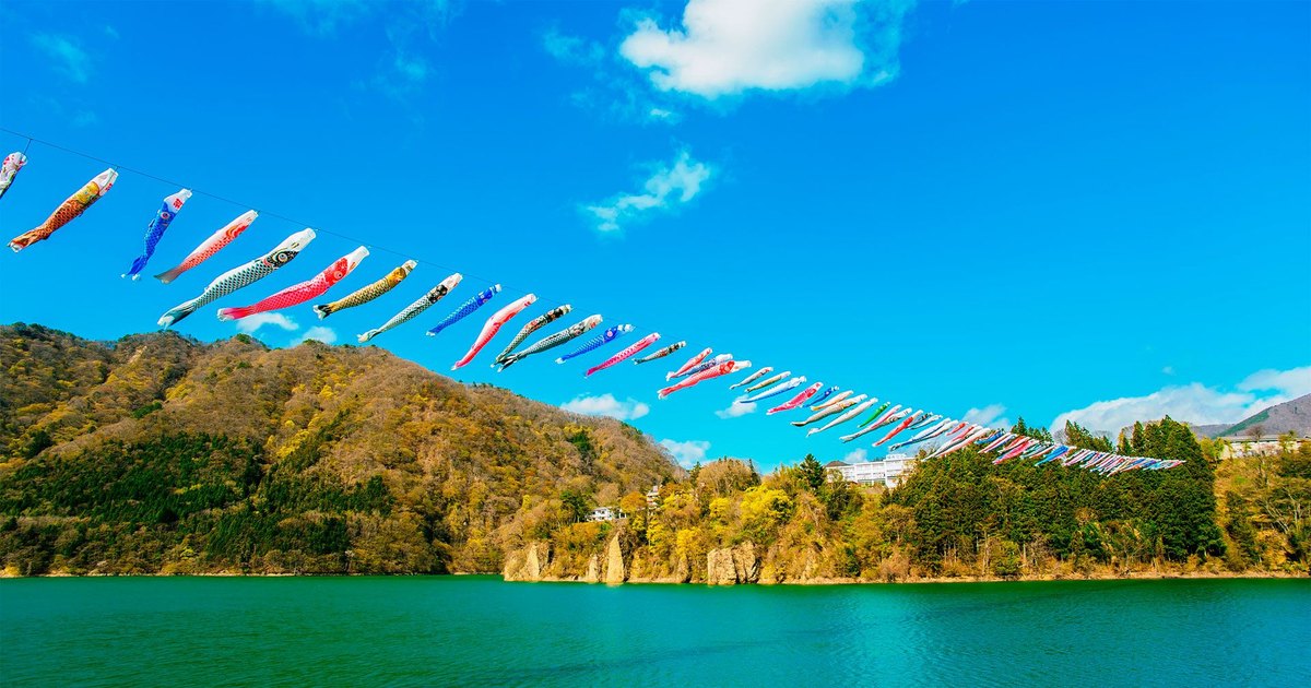 群馬赤谷湖上空拉起一長排彩色鯉魚旗,橫越湖面與早春的山坡