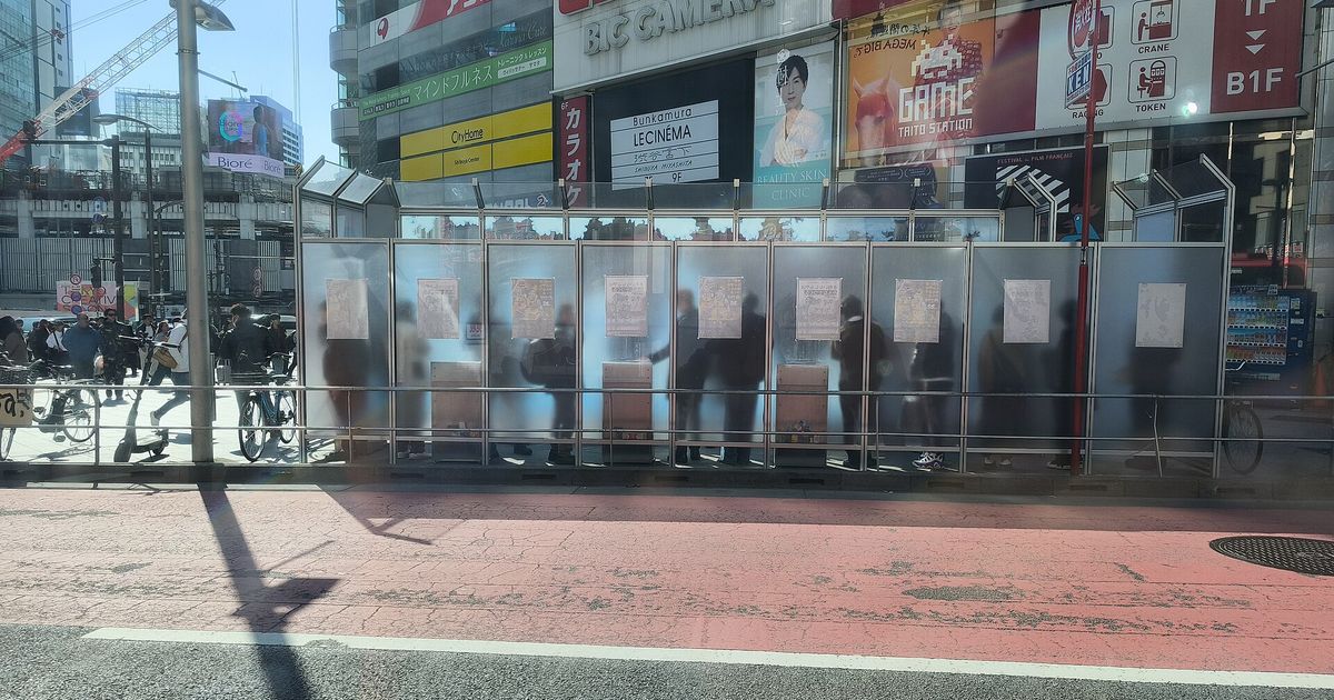 渋谷街頭的圍板式指定喫煙所,半透明隔板內有人吸菸,外側人行道行人與單車往來