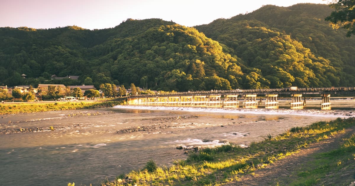 京都嵐山渡月橋與背後嵐山山稜，黃昏暖光