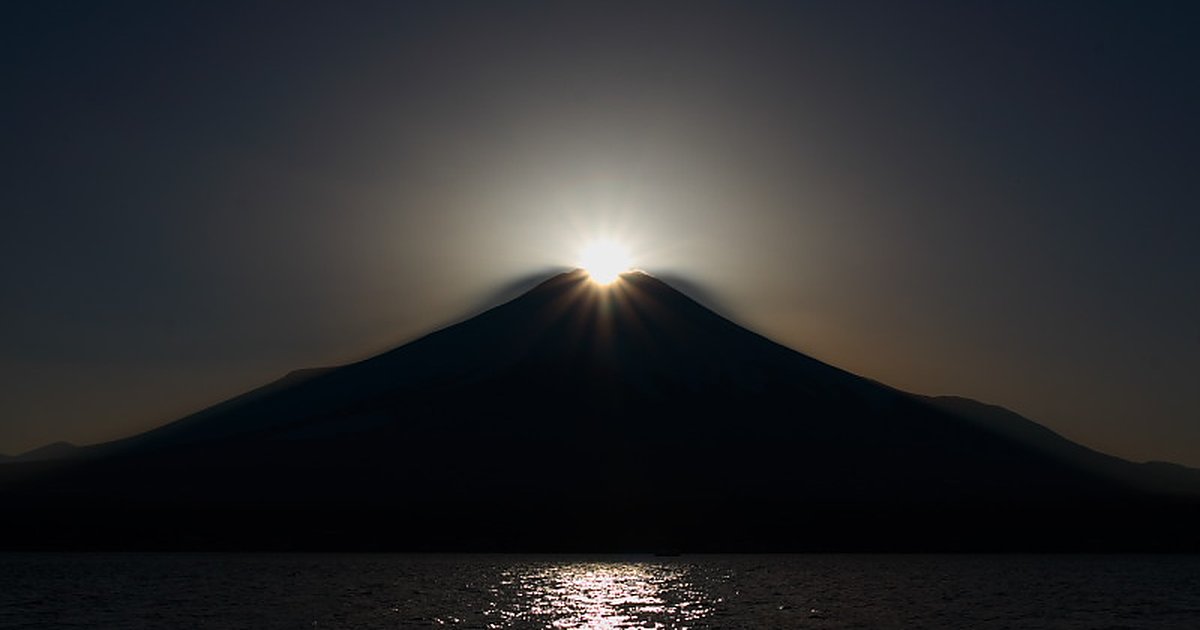 山中湖的鑽石富士:夕陽正好落在富士山頂,山頂迸出一圈放射狀光芒,富士山整座是深色剪影,下方湖面映著一道金色光帶