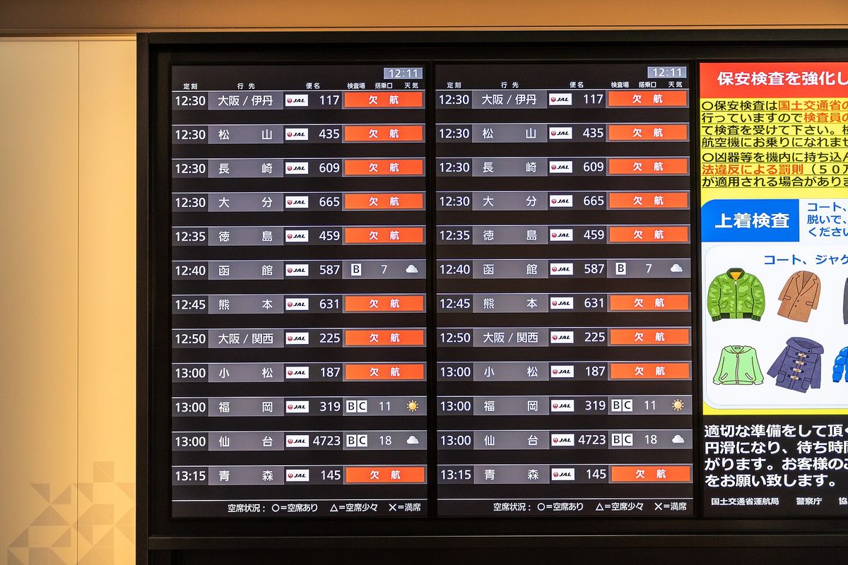 羽田機場 JAL 國內線出發案內看板，多筆班次標示橘色「欠航」，右側欄位以太陽與雲的圖示顯示目的地天氣