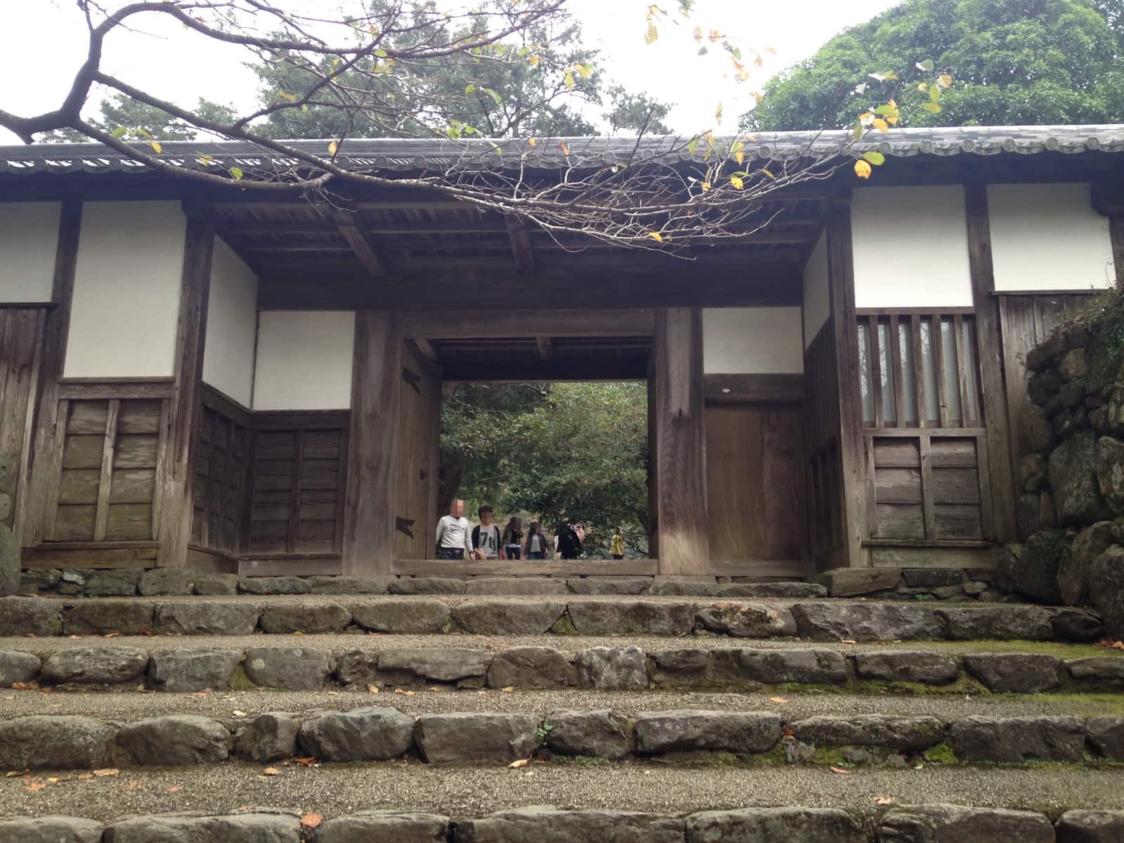 秋月城跡長屋門的木造門面與白牆,門前有石階與樹蔭