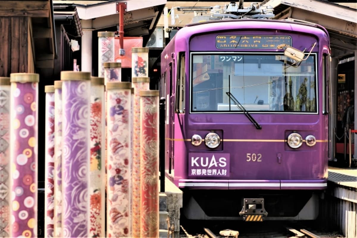 嵐電京福電鐵的紫色車身停靠在嵐山站月台，車站內燈籠裝飾