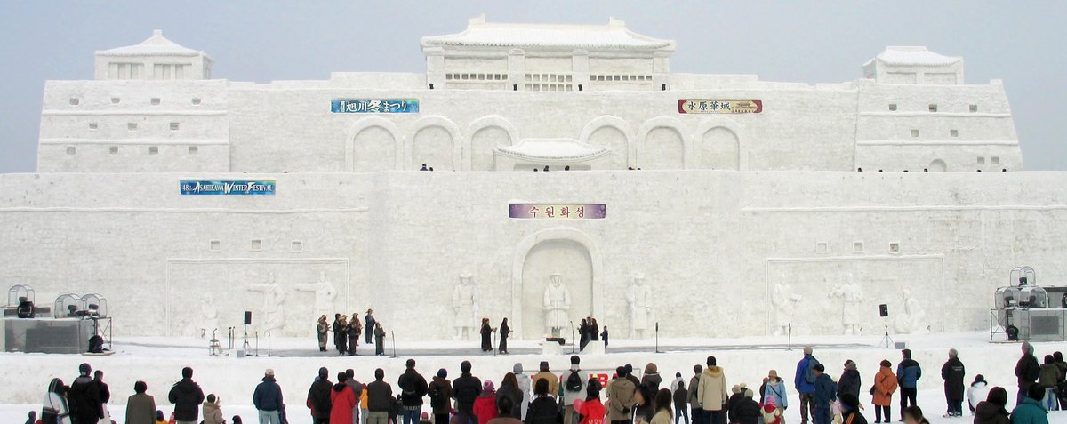 旭川冬祭 2007 年第 48 回的主雪像,仿韓國水原華城城牆與城樓,橫幅寫著旭川冬まつり與水原華城,雪像前方是舞台,遊客站在雪地上看表演