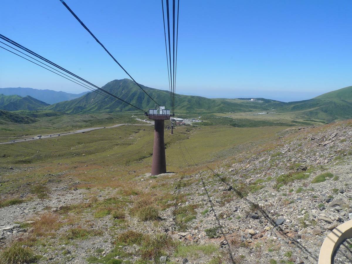 阿蘇山ロープウェー運行時代的吊廂行駛在草原上空,遠方是烏帽子岳