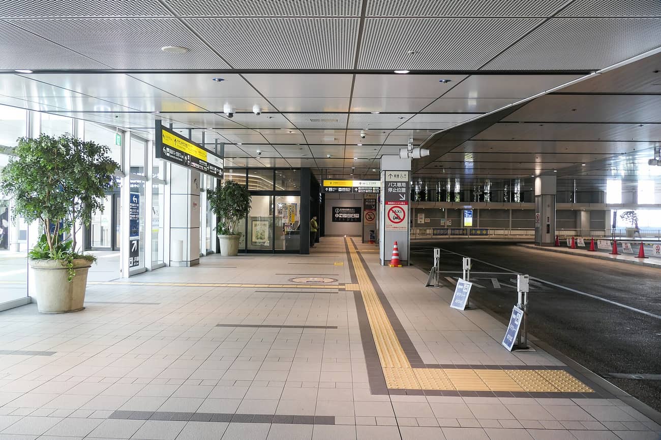 バスタ新宿 3 樓下車專用月台,空無一人的磁磚地面、右側是巴士停車道與計程車招呼站,牆邊有外幣兌換與觀光服務中心
