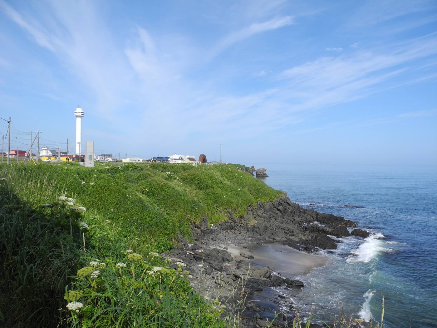 納沙布岬的海岸線與白色燈塔,草坡下方是太平洋礁岩