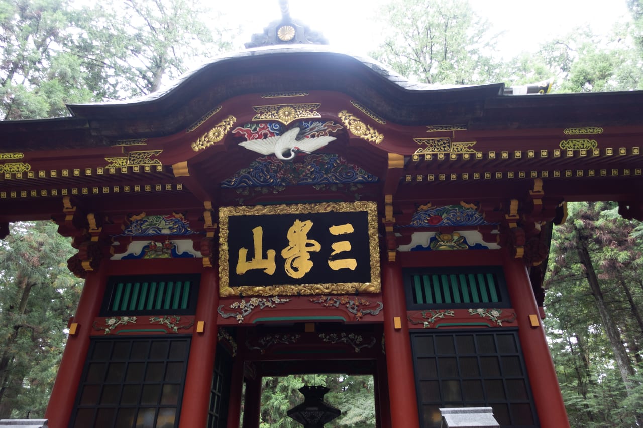 三峯神社隨身門,朱紅與彩繪雕刻的山門被高大杉林環抱