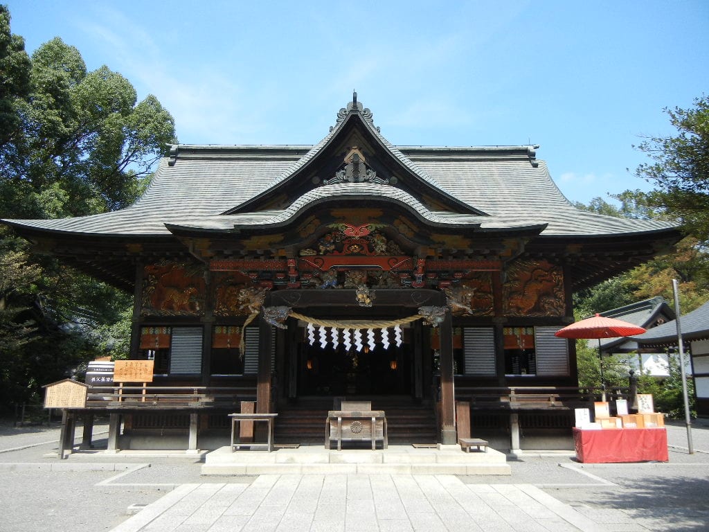 秩父神社朱紅色社殿與精緻彩色木雕,參拜者於本殿前