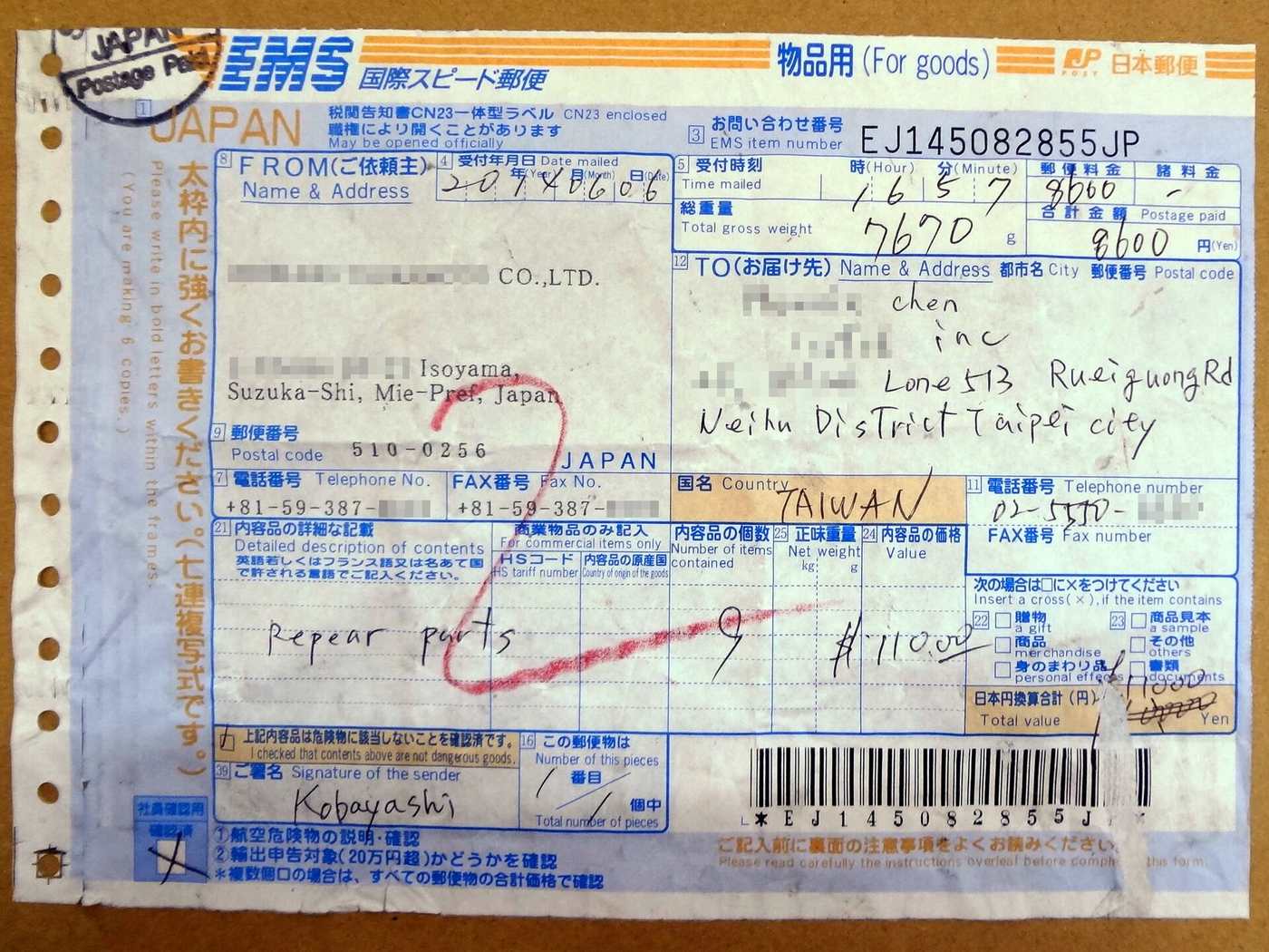 一張填好的日本郵便 EMS 標籤貼在牛皮紙箱上,藍色印刷的表格頂端有 EMS 國際スピード郵便 字樣與橘色「物品用(For goods)」標示,右上角手寫「JAPAN Postage Paid」戳印與單號 EJ145082855JP,寄件人欄是三重県鈴鹿市的公司地址,收件人欄用英文手寫台北市內湖區的地址、国名欄寫著 TAIWAN,料金欄手寫 8600、総重量欄 7670 公克,底部是一道長條碼與寄件人簽名