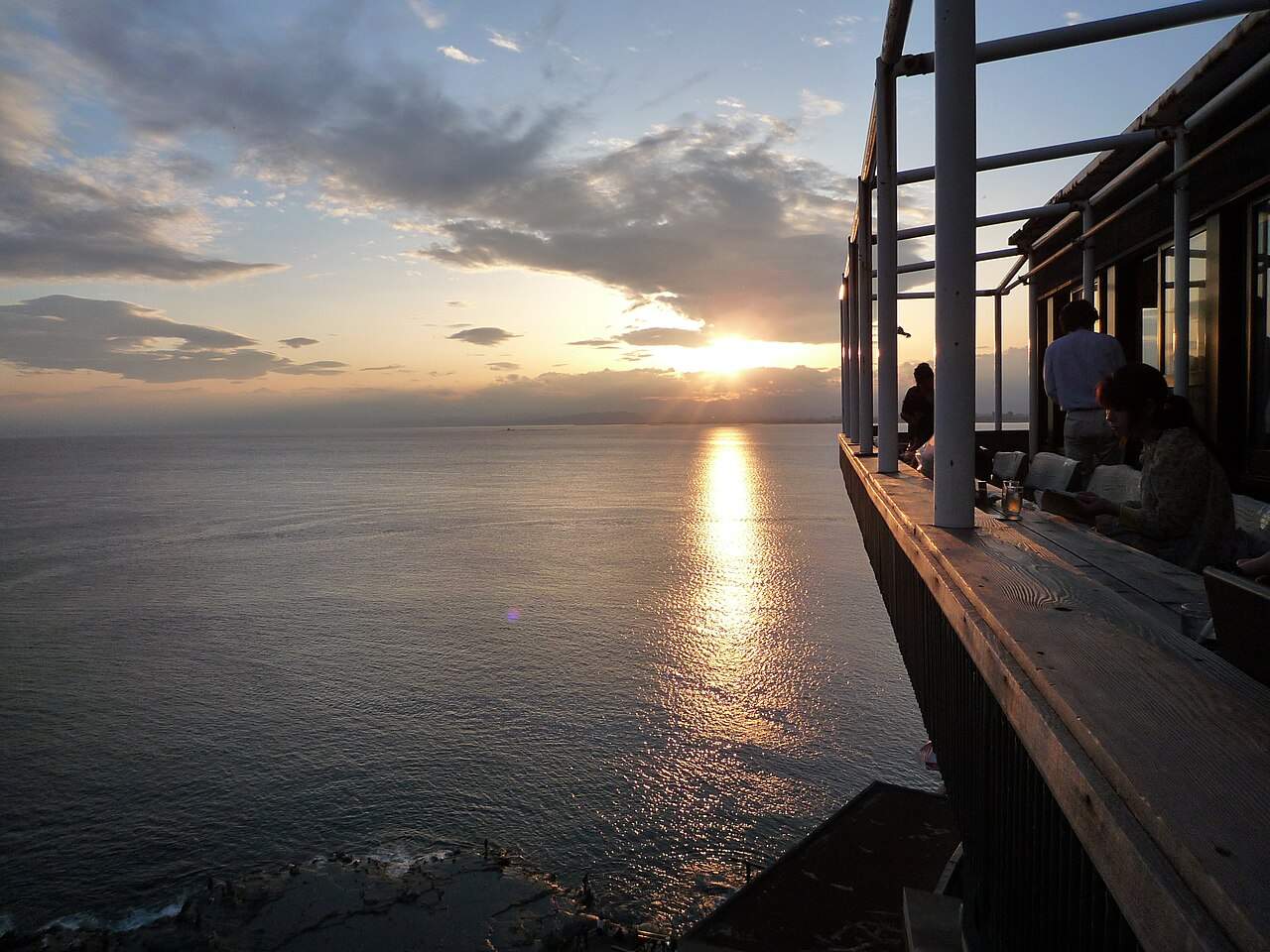 魚見亭的露天座位懸在崖邊,客人正對相模灣海面上的夕陽用餐