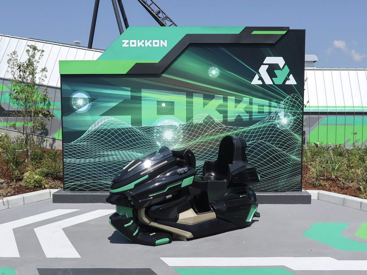 ZOKKON 入口前展示的摩托車型車輛與綠黑配色品牌牆,背景可見軌道支架