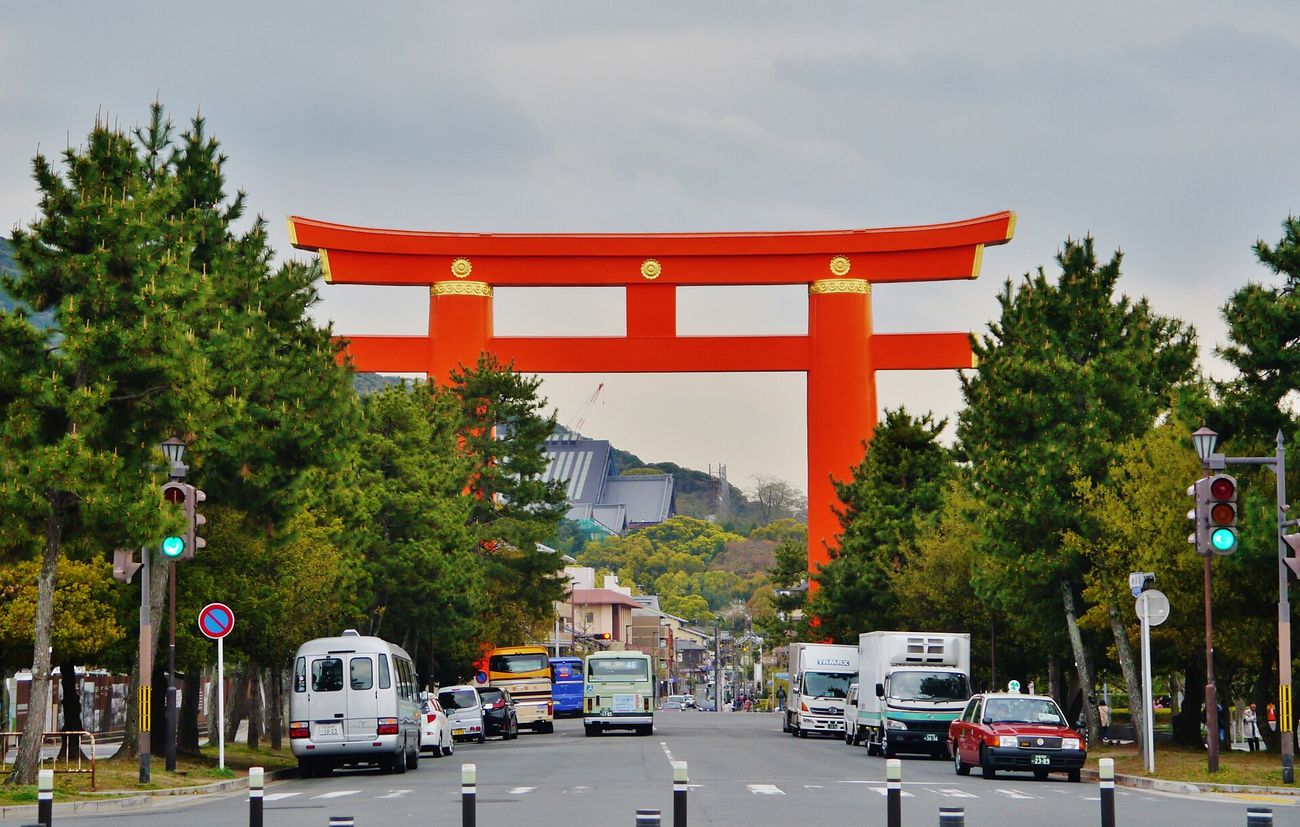 平安神宮的朱紅色大鳥居橫跨神宮道,兩側是松樹與市區車流