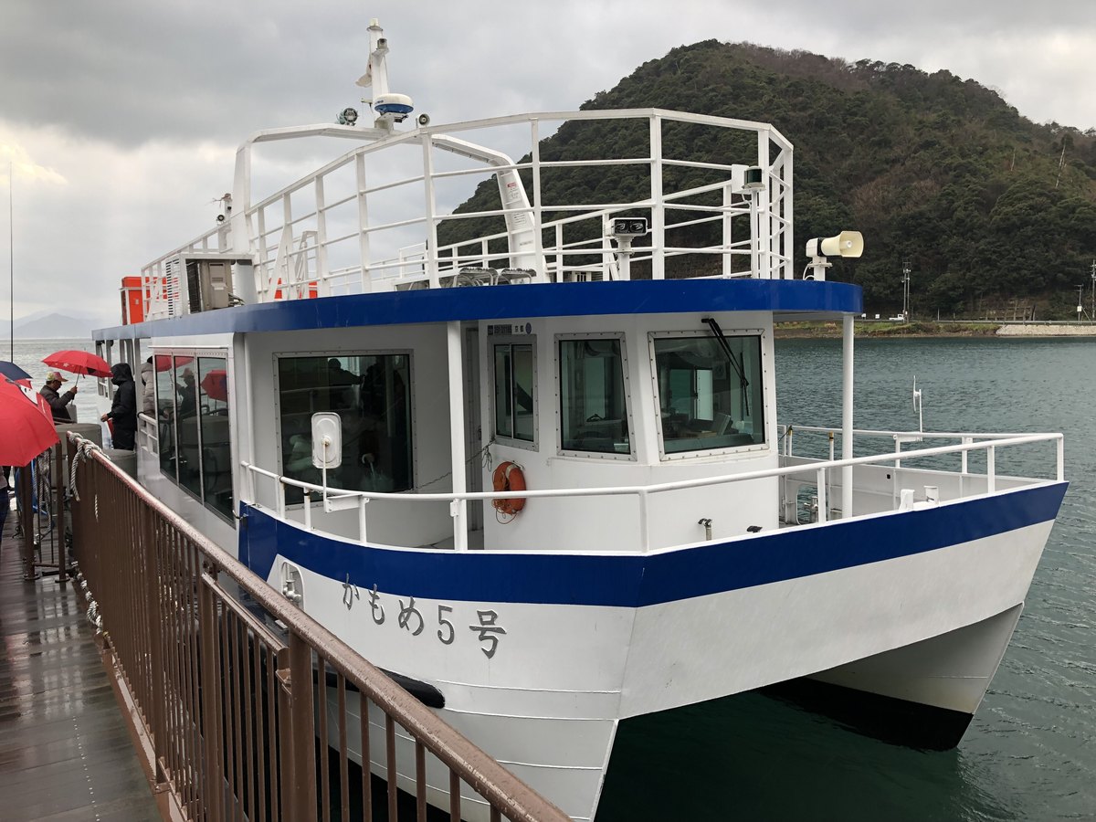 伊根灣遊覽船「かもめ5號」停靠在棧橋邊，雨天，岸上旅客撐著傘等候上船