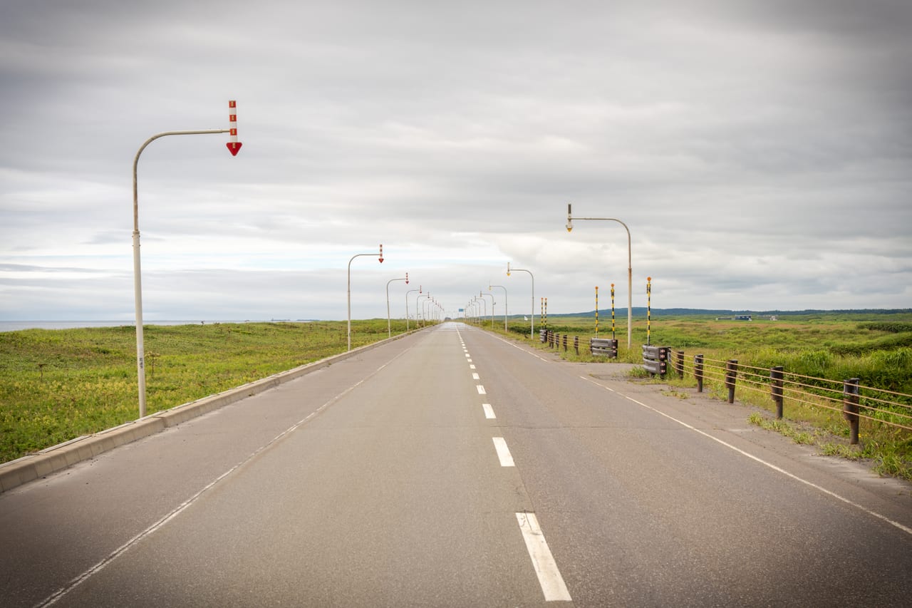 北海道筆直公路的自駕風景,兩側遼闊原野與藍天,日本租車自駕的經典畫面