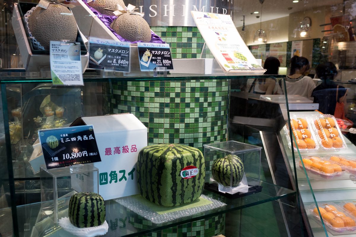 東京澀谷高級水果店櫥窗,綁緞帶的網紋哈密瓜禮盒與方形西瓜,標示日圓禮盒價格