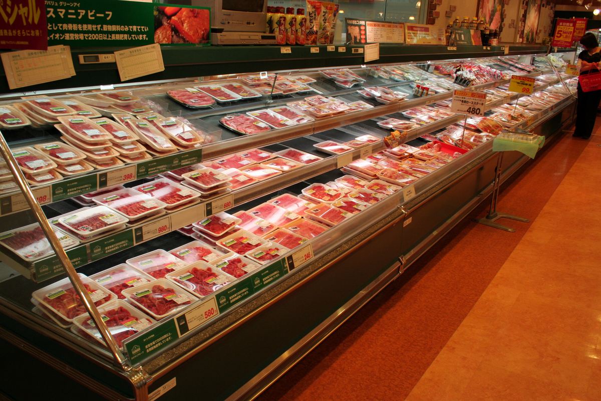 日本超市的精肉冷藏櫃,一整排盒裝生鮮牛肉與豬肉,標示日圓價格