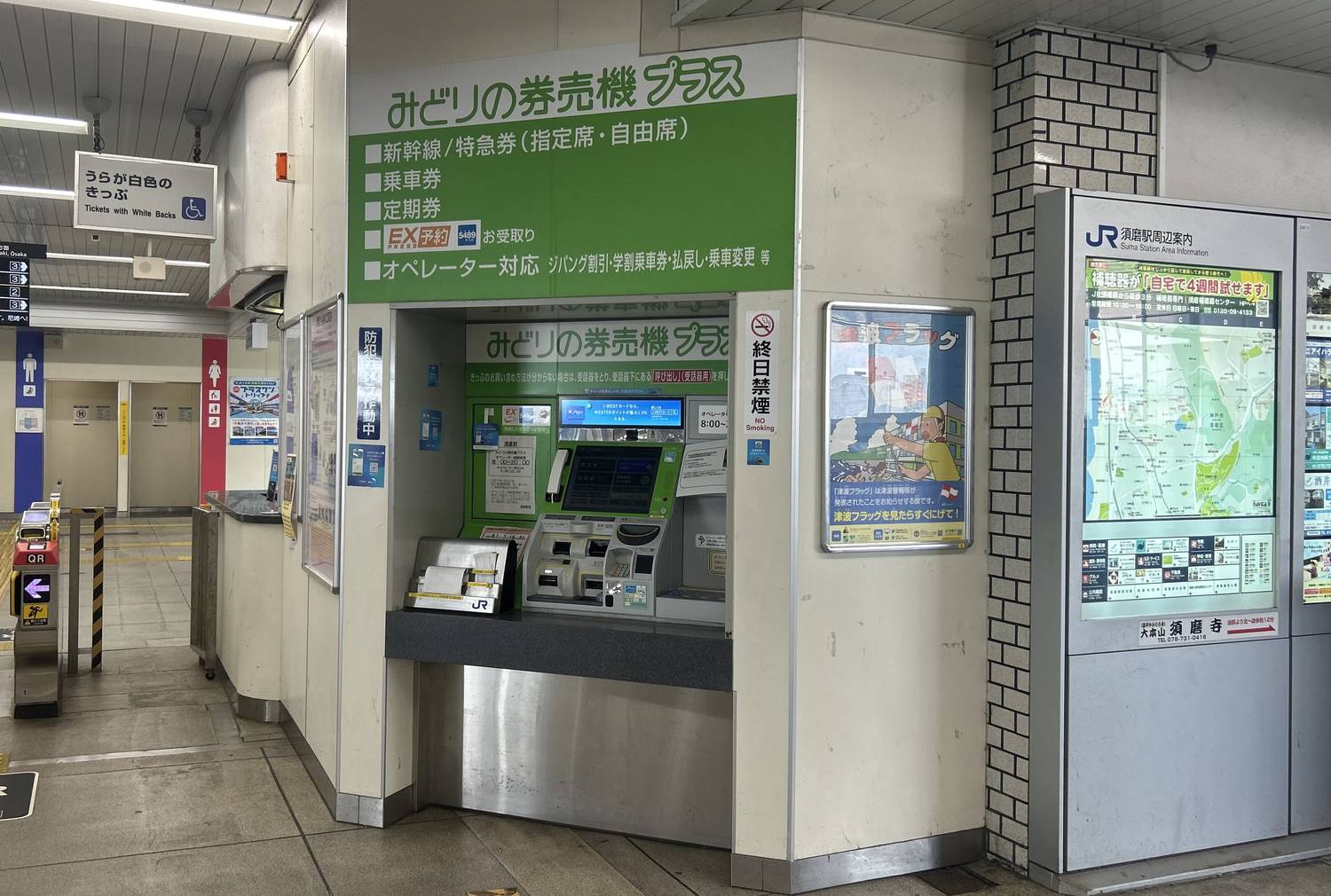 JR 車站內的售票機區:牆上一整片綠色看板,最上方大字寫著「みどりの券売機プラス」,下方條列「新幹線/特急券(指定席・自由席)」「乘車券」「定期券」「EX 予約 お受取り」「オペレーター對應」;凹進去的空間裡放著一台綠色機身的觸控式售票機,右側是站區導覽看板