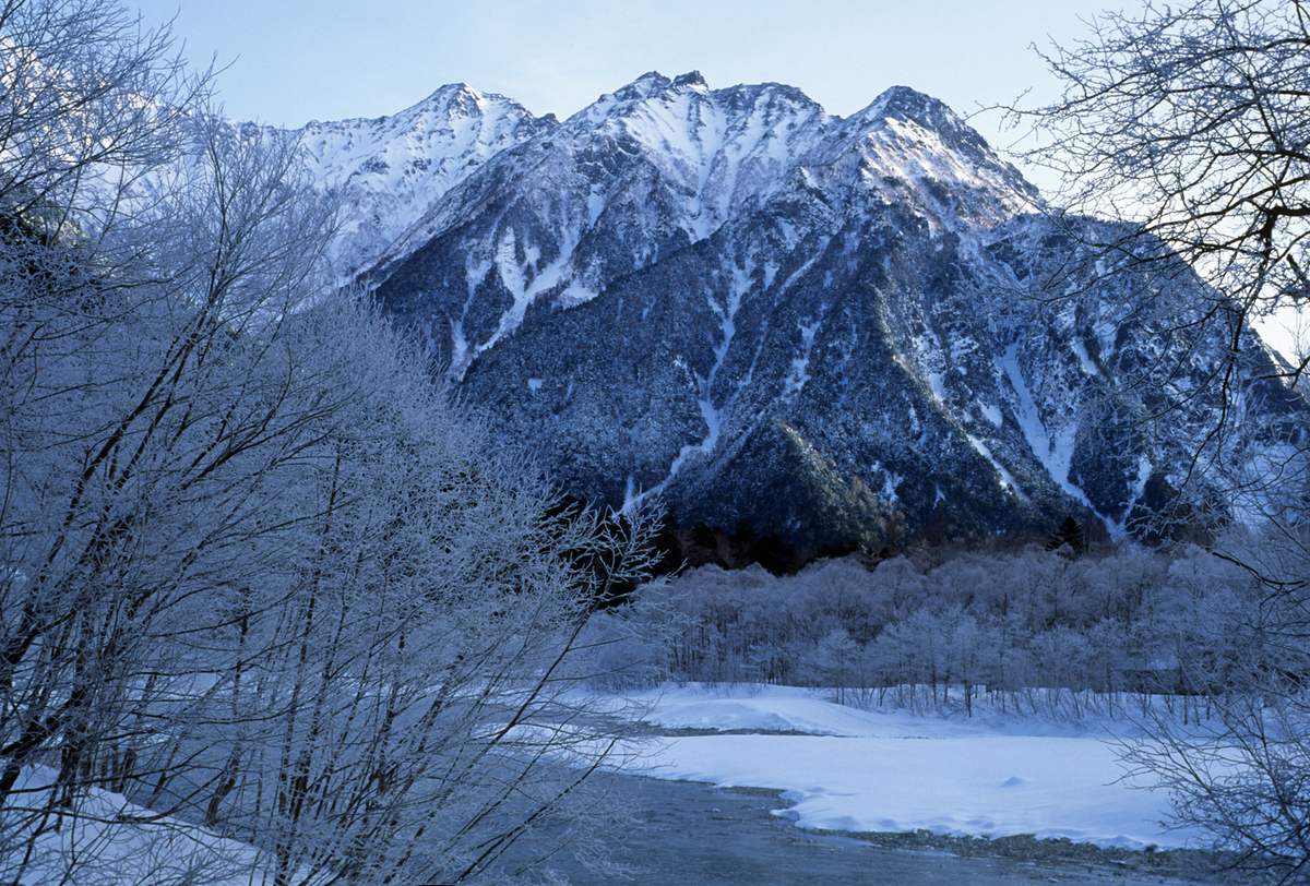 冬季雪封的上高地與前穗高連峰，梓川半結冰、河岸樹木掛滿霧淞