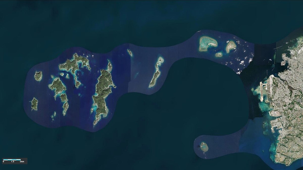 慶良間諸島的衛星影像,一群深綠色小島散在深藍海面上,島群外圍套著一圈顏色較淺的藍色範圍框,右側是沖繩本島南部與那霸市區,左下角有 0 到 3 公里的比例尺