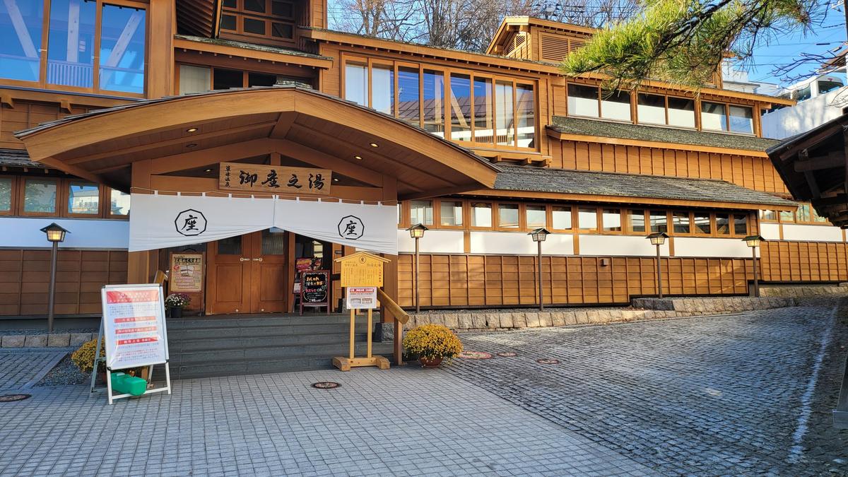 御座之湯正面，木造兩層建築，入口掛著印有「座」字的白色暖簾