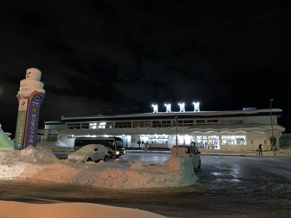 北海道倶知安町車站前的冬夜:除雪堆起的雪牆比人還高,停在旁邊的轎車幾乎被雪整台埋住