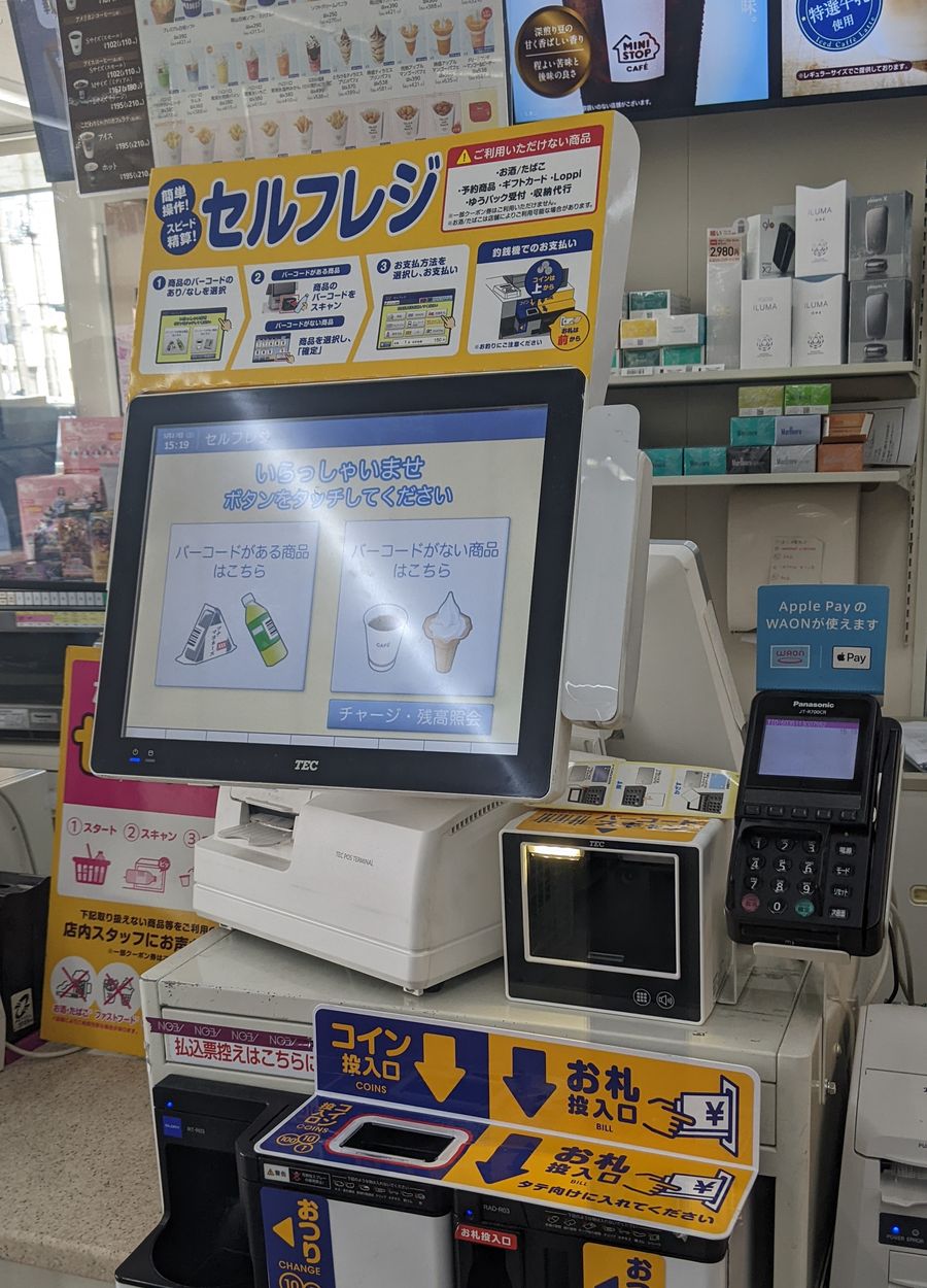 MINISTOP 店內的自助結帳機：上方黃色看板寫著「セルフレジ」與四個步驟的操作圖示，右上角紅框標題「ご利用いただけない商品」底下列出お酒／たばこ、予約商品、ギフトカード、Loppi、ゆうパック受付、収納代行；螢幕顯示「いらっしゃいませ ボタンをタッチしてください」與兩個選項按鈕，下方是硬幣與紙鈔投入口，櫃檯前緣另有一條紅字寫著「払込票控えはこちらに」