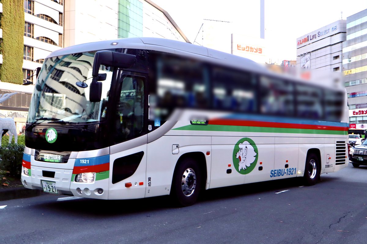 西武観光バス的白色高速巴士停在池袋站東口，車身有藍紅綠三色線條和獅子圖案，車頭與車側的行先顯示寫著「苗場プリンスホテル」