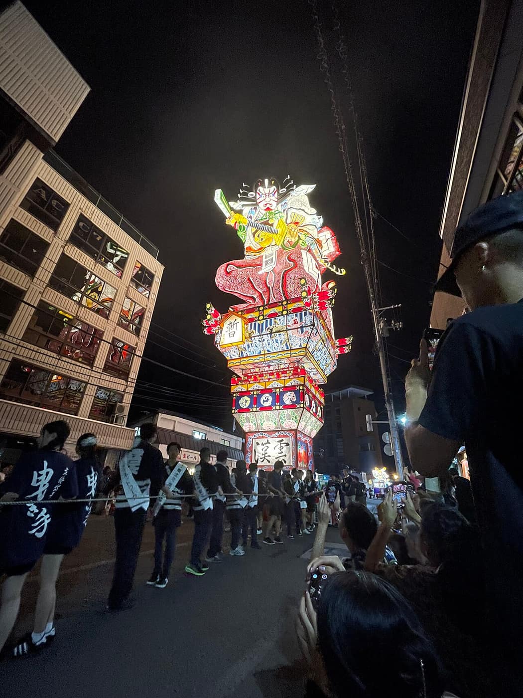 五所川原立佞武多的直立式巨型燈籠在夜間街道運行,高度超過兩側樓房