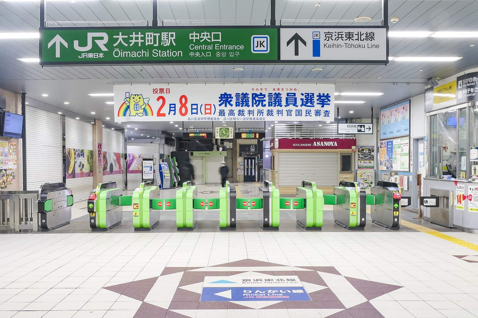 JR 大井町站中央口一整排綠色自動改札機,上方綠底白字指示牌寫著「大井町駅 中央口 Central Entrance」,旁邊另一塊寫著「京浜東北線」,閘機側面有橘色的 IC 感應區,地板上貼著京浜東北線與りんかい線的方向箭頭
