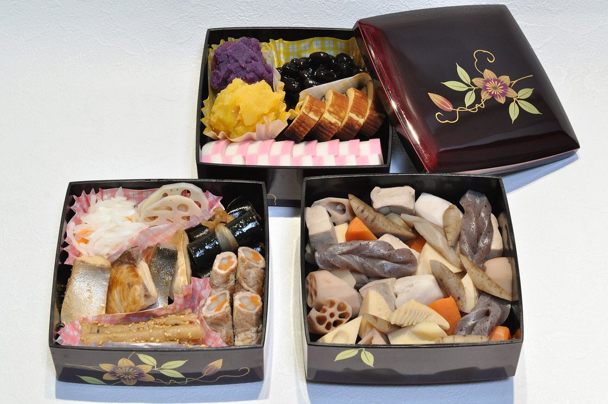 三層漆器重箱裝的おせち料理，內有黑豆、栗きんとん、伊達卷、紅白蒲鉾、煮しめ與魚料理