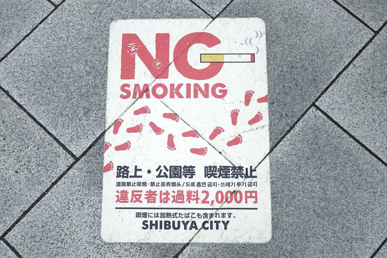 渋谷人行道地面上的 NO SMOKING 路上禁菸貼標,寫著路上・公園等喫煙禁止與違反者過料 2,000 円