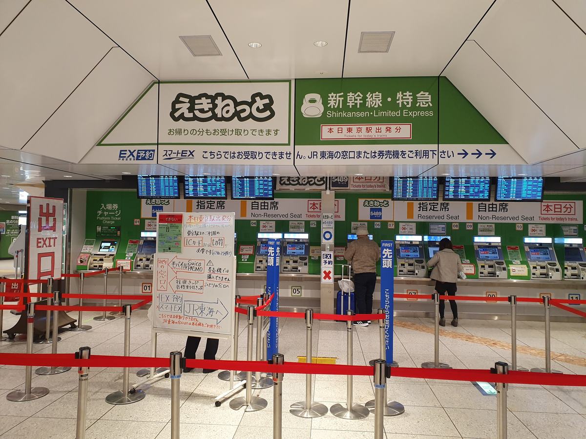 東京站 JR 東日本的新幹線・特急券售票機區,綠色機台分成指定席與自由席,上方橫幅寫著 EX 予約與スマートEX 在此無法取票、請改用 JR 東海的窗口或券売機