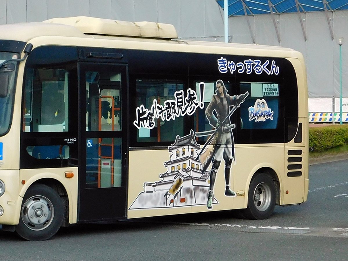 白石市民巴士「きゃっするくん」的小型 Hino Poncho 巴士側面,米色車身上畫著白石城與持刀的武將插畫,右上角寫著「きゃっするくん」,車窗貼著「白石市 有償運送車両」標示