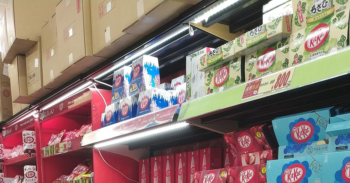 日本貨架上陳列的多種口味地區限定 KitKat 與包裝零食,常見的伴手禮採買畫面