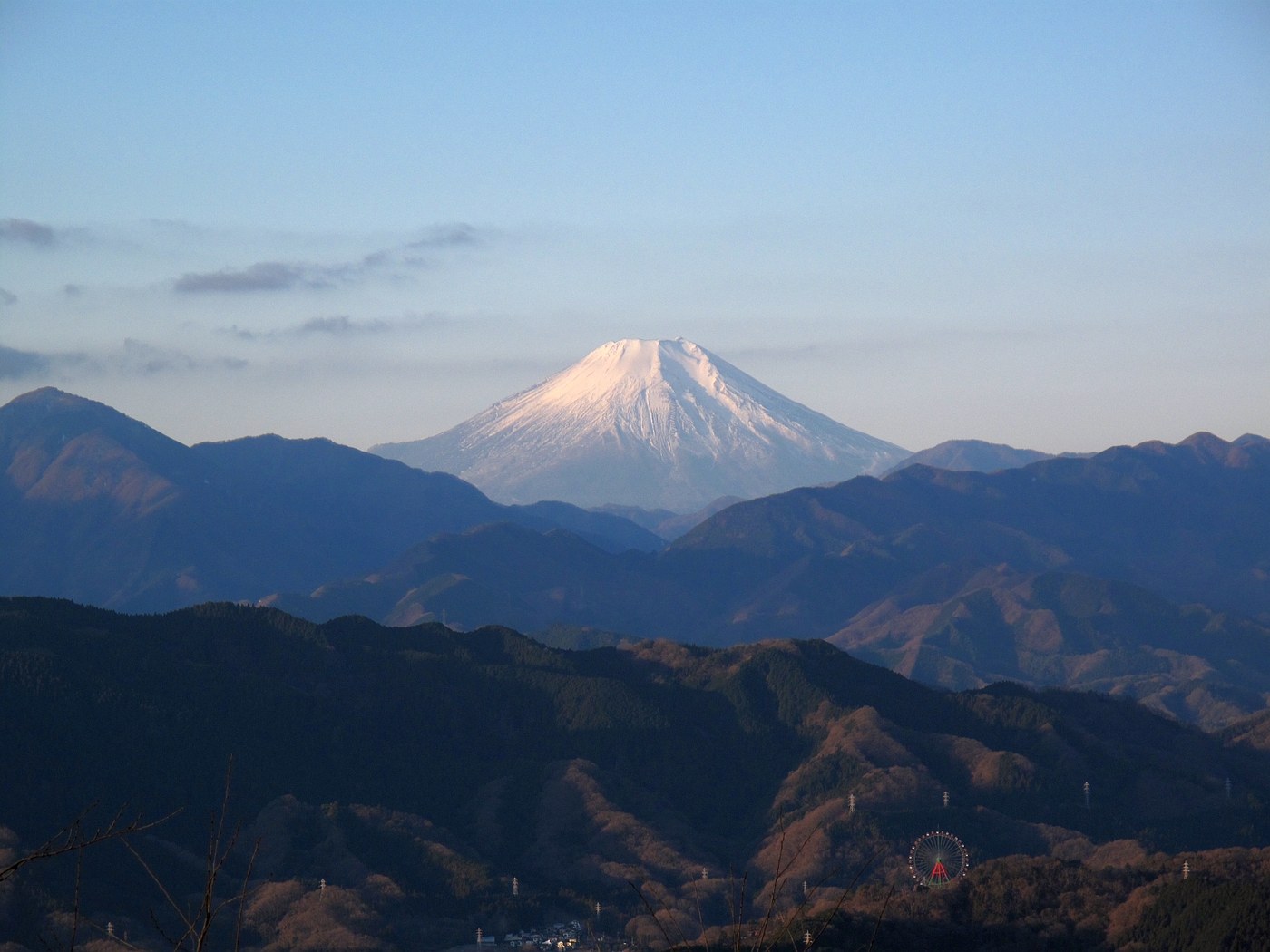 冬季高尾山山頂望向積雪的富士山,前景是落葉後的丹沢山地稜線