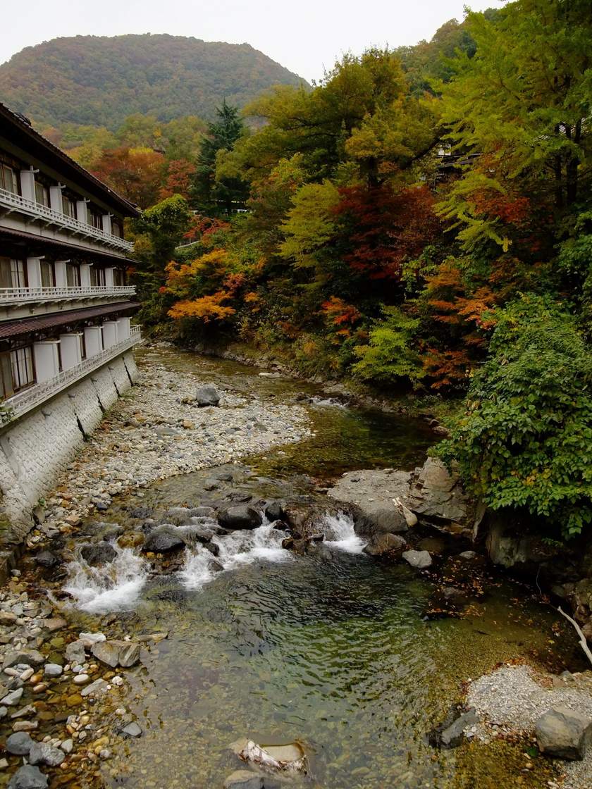2009 年 10 月下旬的寶川溪谷:左岸是沿著石砌河堤蓋的多層旅館建物,右岸的樹紅、黃、綠夾雜,河床上是卵石與淺淺的急流