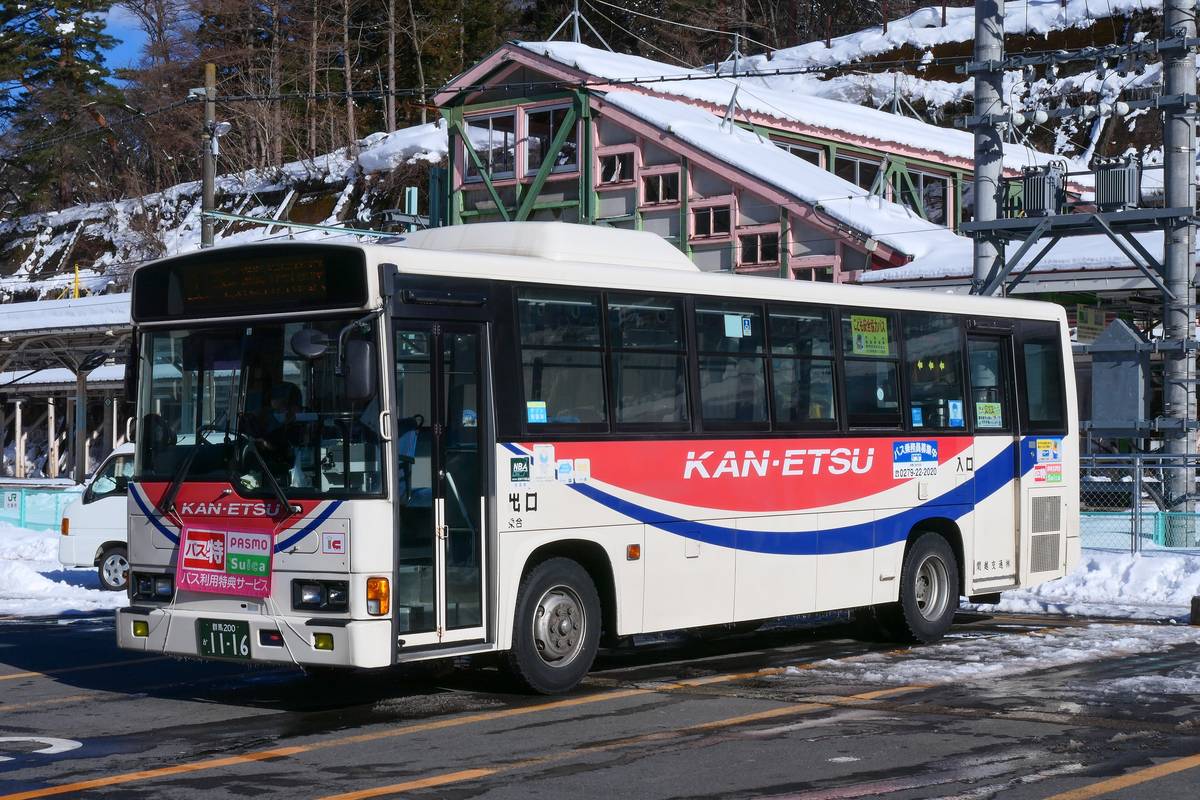 雪後的水上駅前,一輛紅藍白塗裝、車身印著 KAN-ETSU 的關越交通路線巴士,車頭掛著 PASMO 與 Suica 的牌子