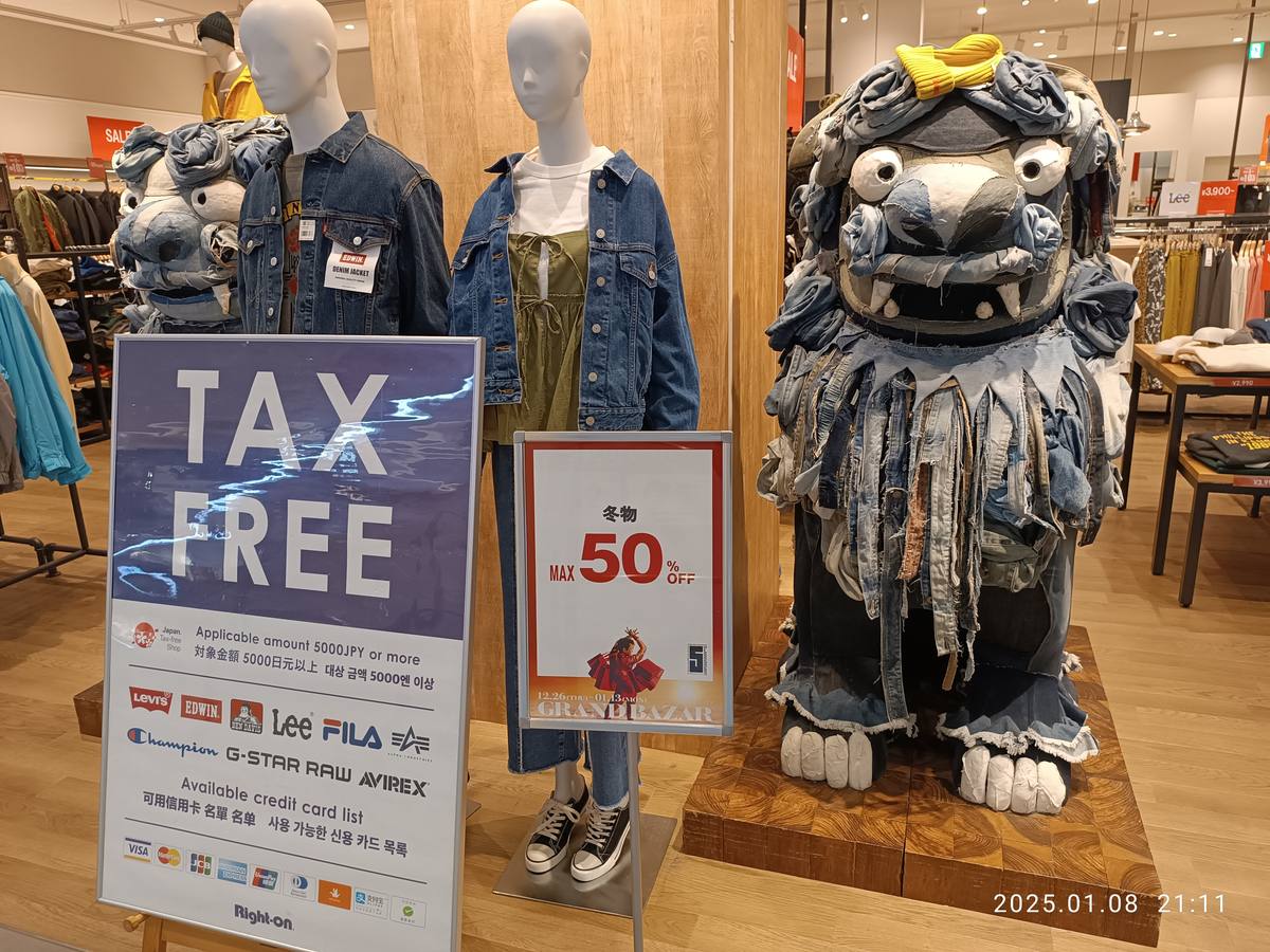 日本商場服飾店賣場內立著的 TAX FREE 告示牌,載明適用金額 5,000 日圓以上與可用信用卡