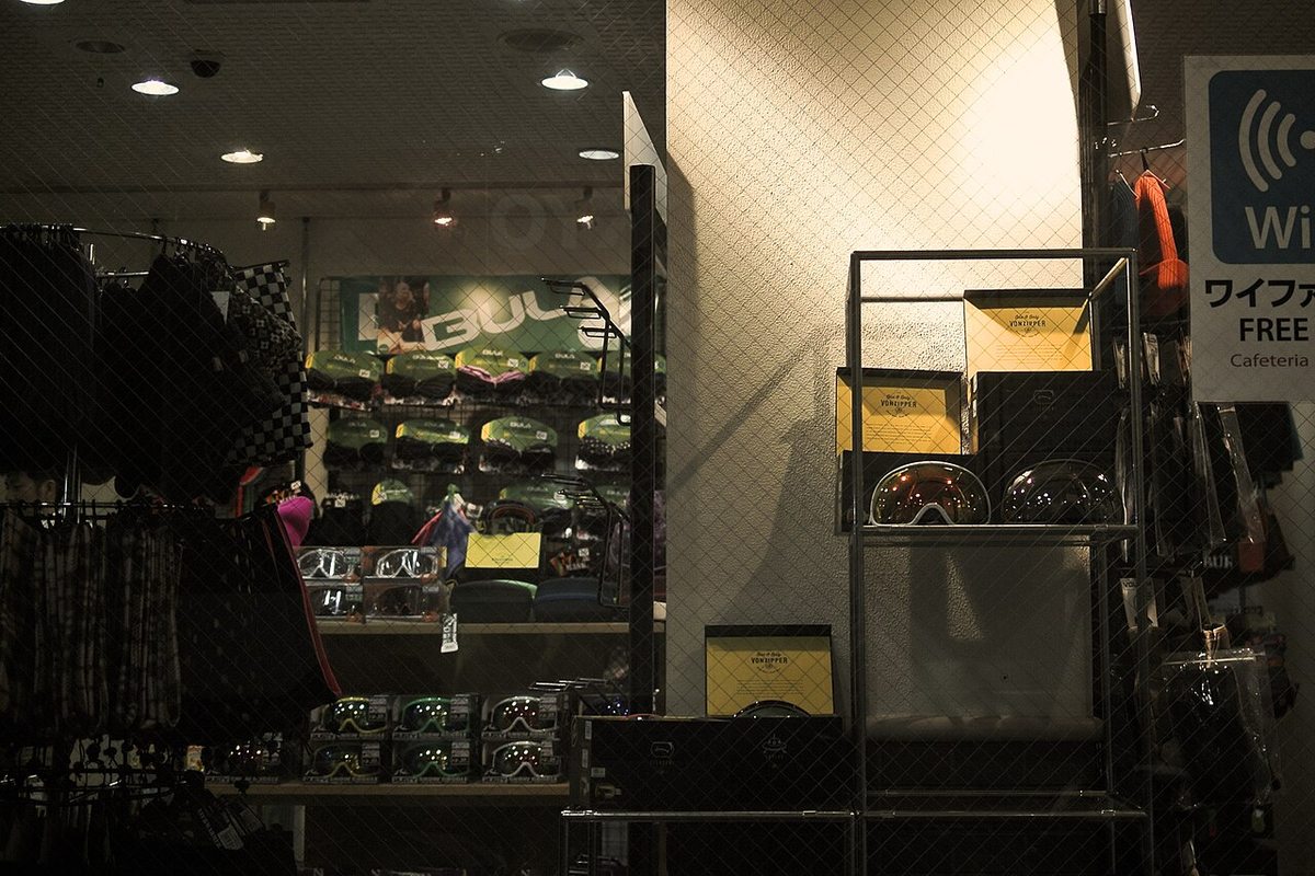 サッポロテイネ 場內店面的貨架,排滿盒裝護目鏡、毛帽與頭巾,右上角掛著日文的免費 Wi-Fi 與 Cafeteria 告示牌