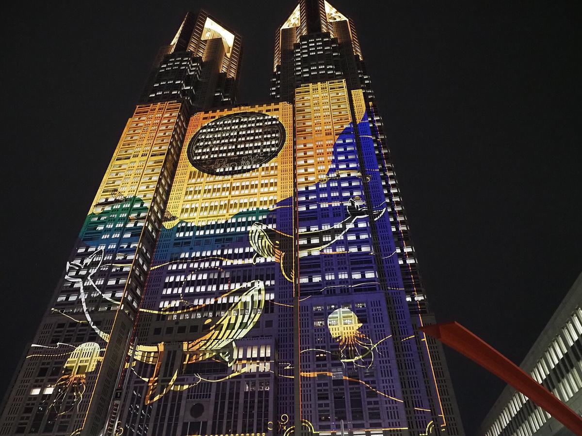 東京都庁第一本廳舍雙塔外牆被投影 mapping 打上藍黃色圖樣的夜間仰角