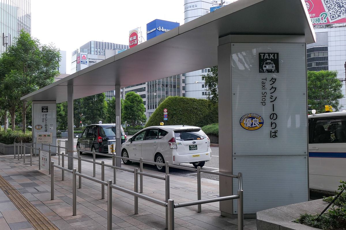 東京車站八重洲口的計程車招呼站,「タクシーのりば/Taxi Stop」立柱與排隊護欄旁停著數台計程車