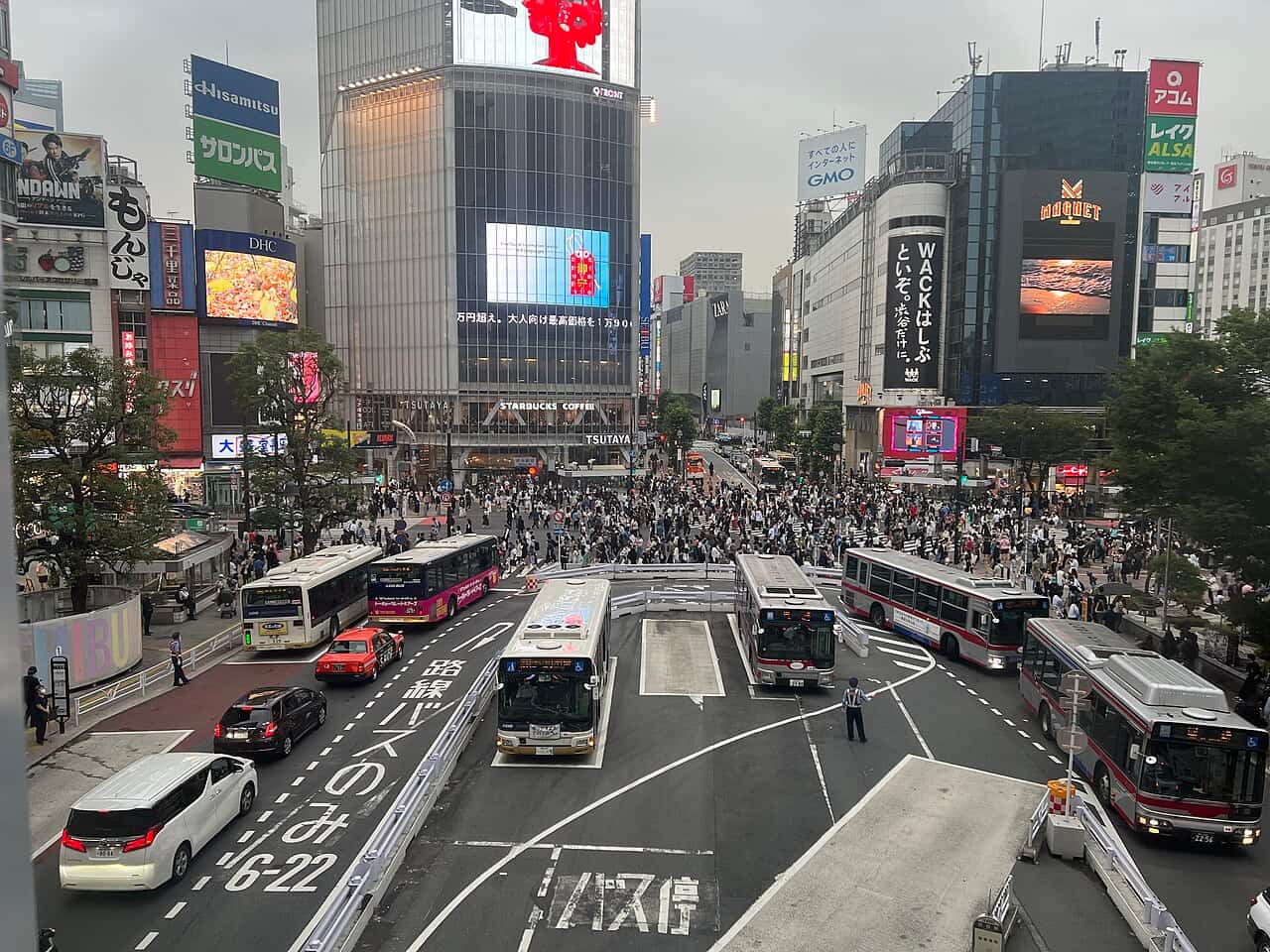 東京澀谷十字路口擠滿穿越馬路的人潮,四周是高樓與霓虹廣告牆