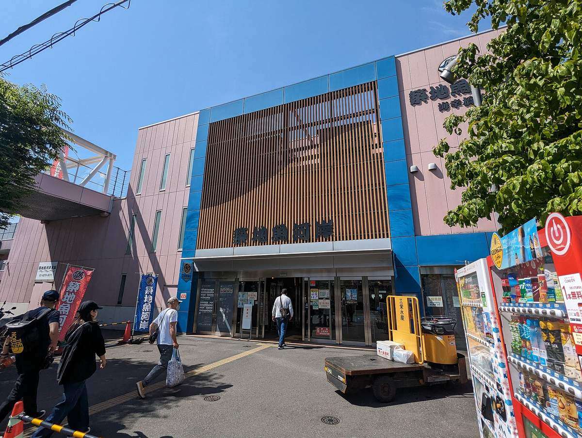 築地魚河岸海幸橋棟的建物外觀,正面木格柵下方是「築地魚河岸」字樣與自動門入口,門前立著藍色幟旗