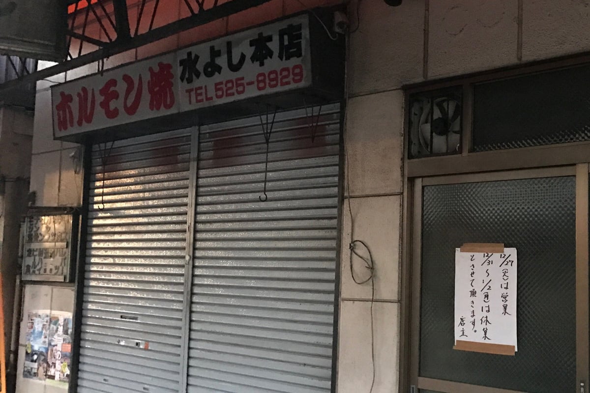 日本埼玉縣熊谷市一家名為「ホルモン焼 水よし本店」的燒肉店,入口鐵捲門整片拉下,右側玻璃門上用膠帶貼著一張手寫直式白紙,寫著「12/27(火)は営業 12/31〜1/2(月)は休業とさせて頂きます。店主」
