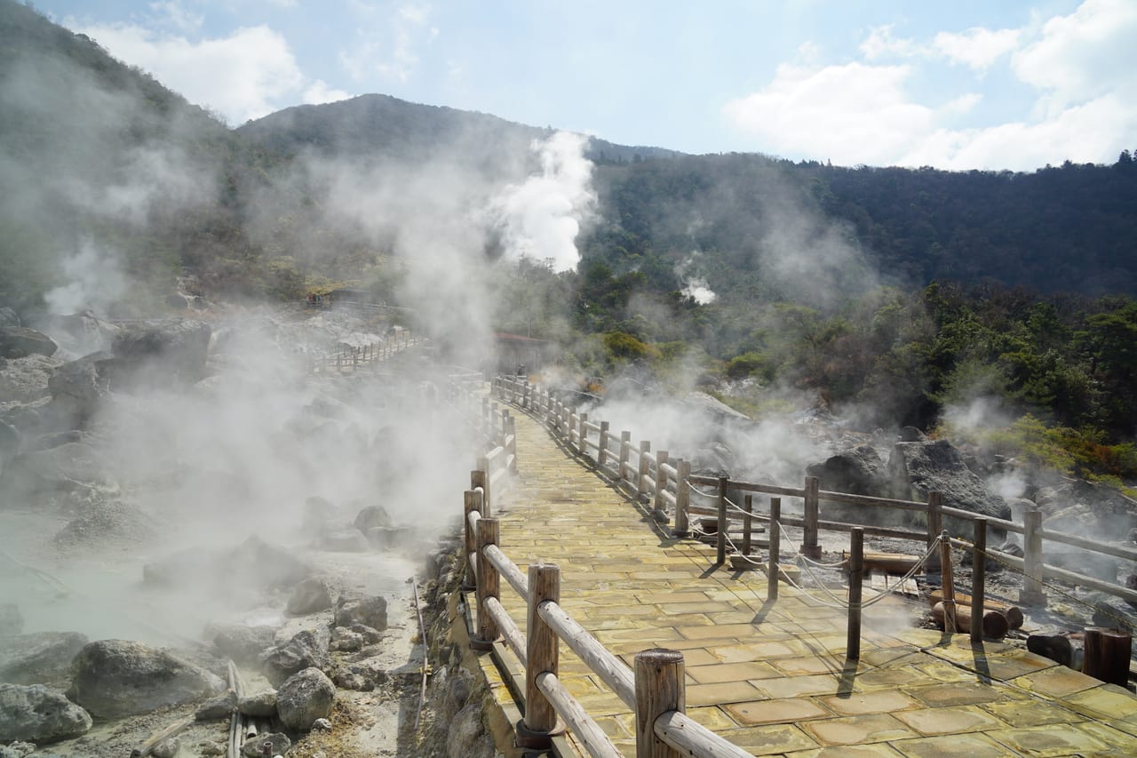 雲仙地獄噴著白色硫磺蒸氣的地熱原與木棧步道,就在溫泉街旁邊
