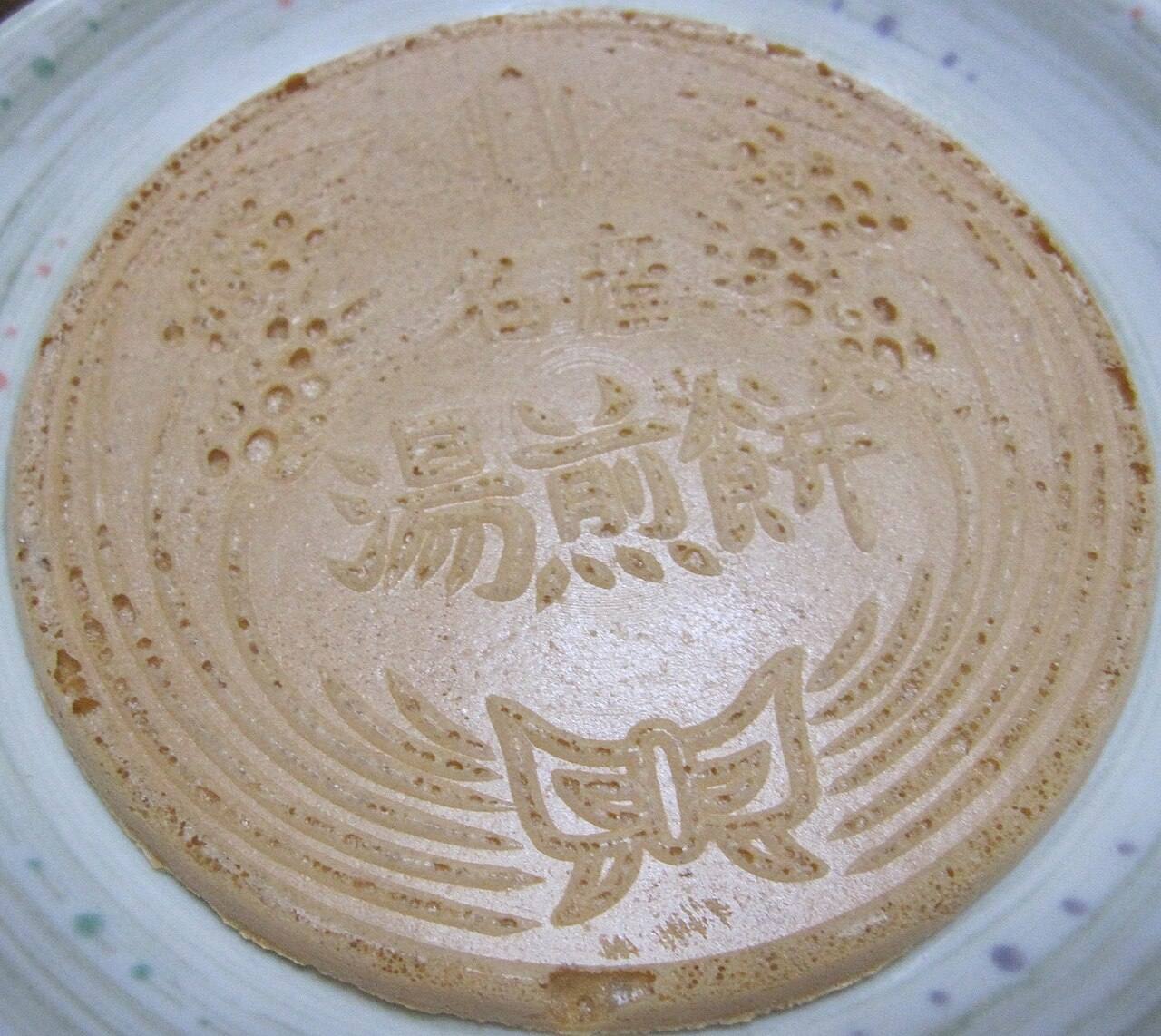 湯せんぺい特寫,餅面烙有「名產 湯煎餅」字樣與花紋