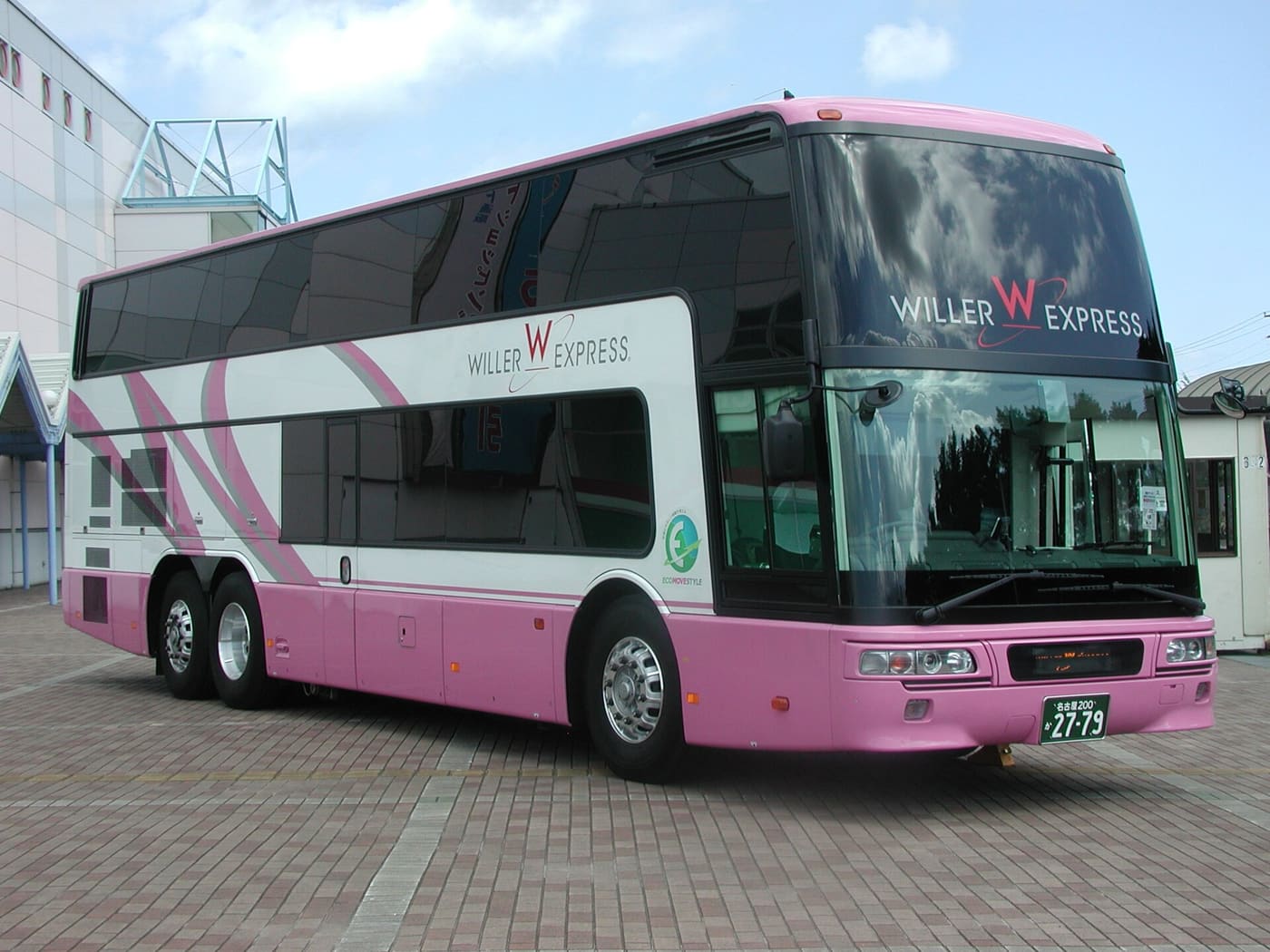 粉紅與白色塗裝的 WILLER EXPRESS 雙層巴士停在磚地上,車身側面下半部是平整的粉紅色板面,看不到大型行李艙門
