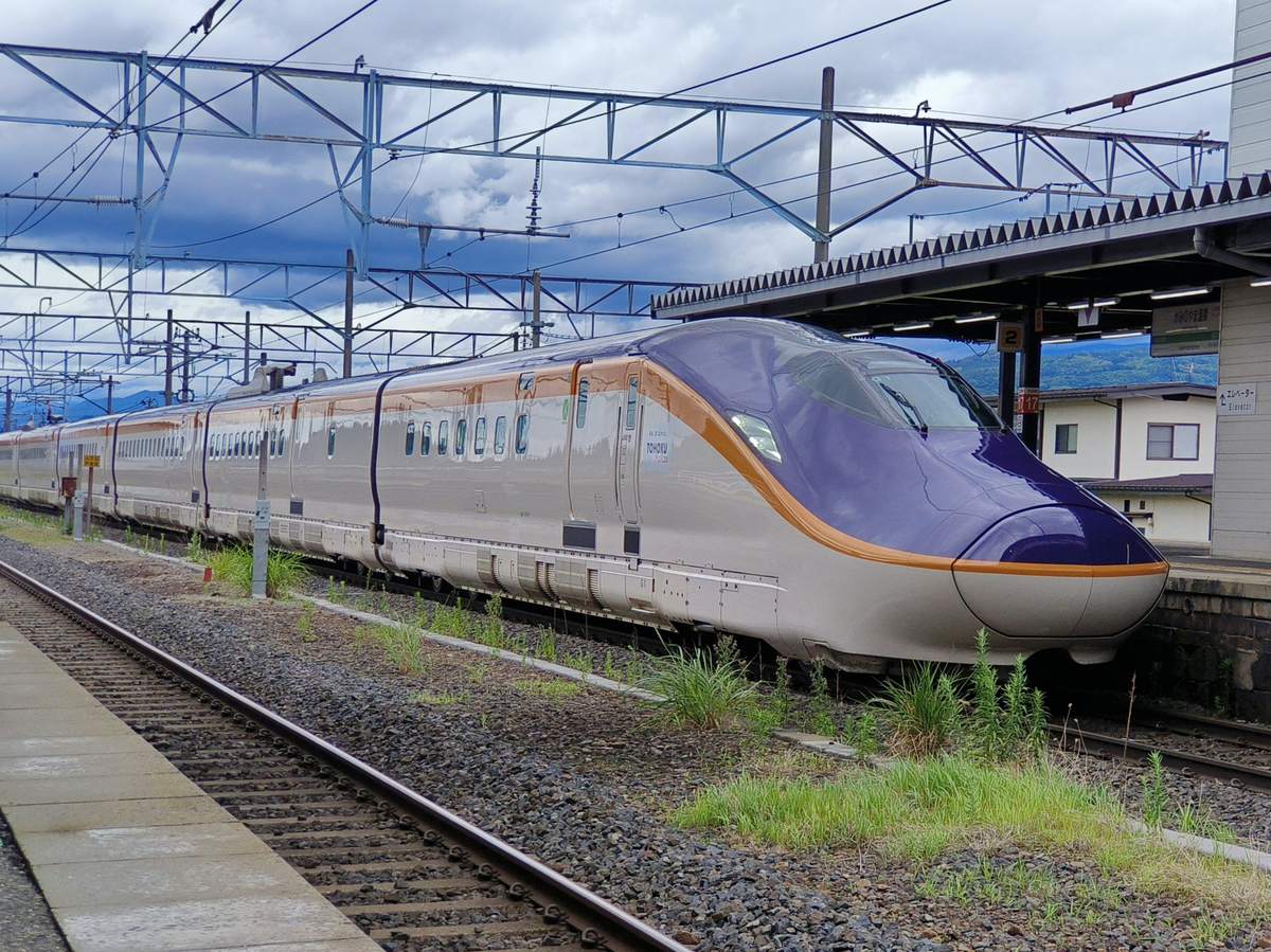 山形新幹線 E8 系「つばさ」停靠山形線月台,紫金配色的車頭與月台雨棚